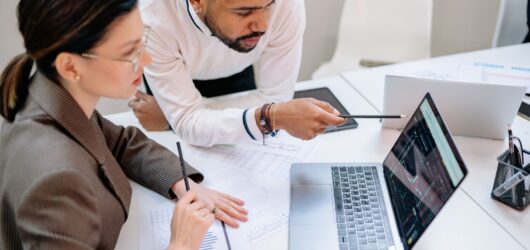Two business professionals reviewing analytics on a laptop